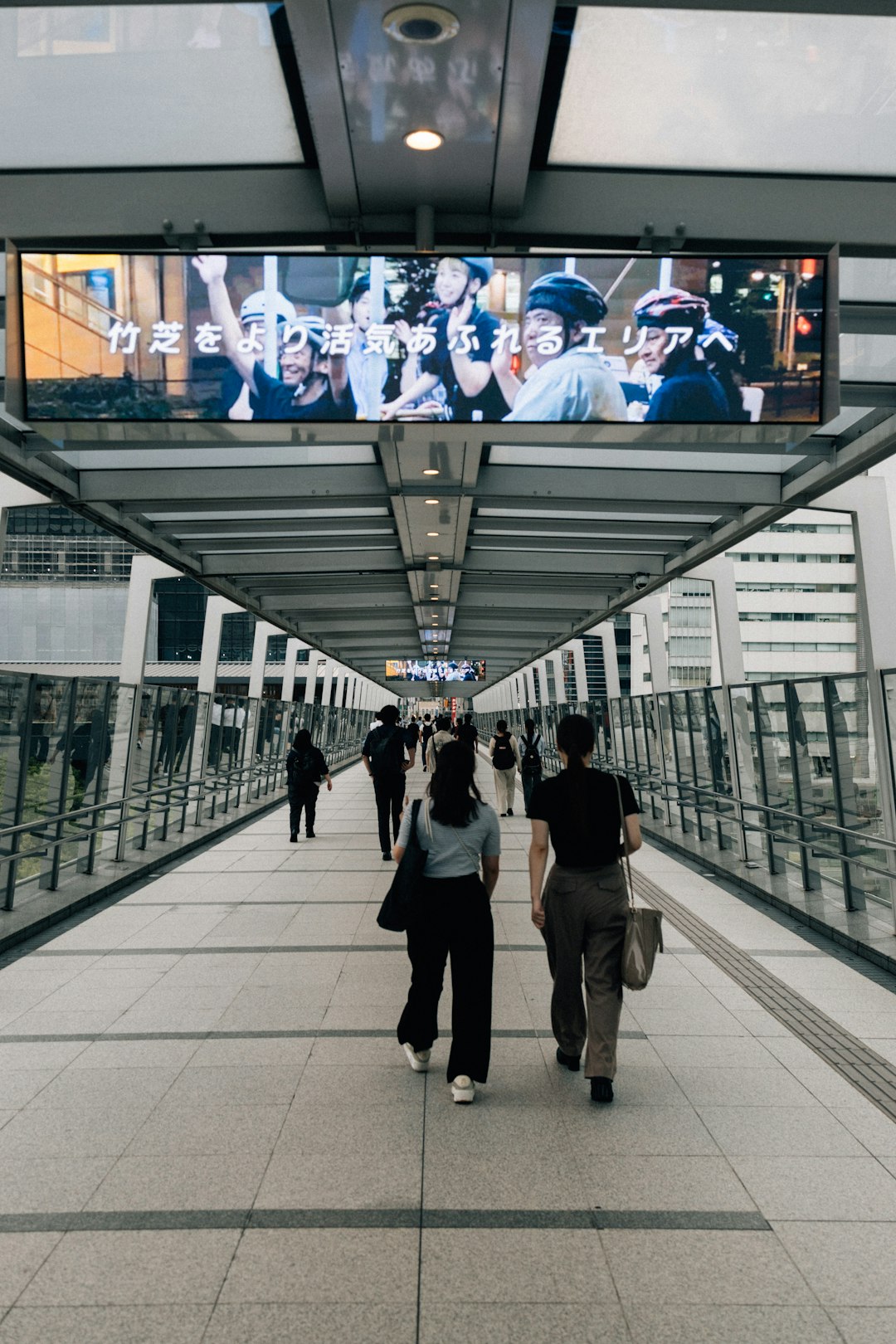 people-walking-on-a-modern-elevated-walkway-with-advertisements-id5bopwrrmg